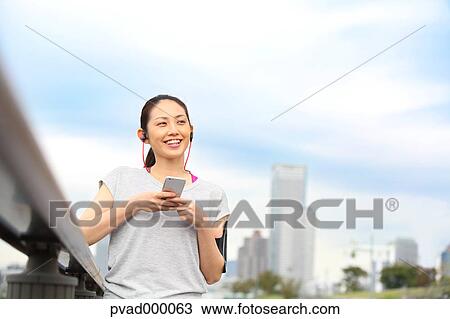 Attractive Japanese woman listening to music by a river downtown Tokyo, Japan View Large Photo Image Stock Image - Attractive Japanese woman listening to music by a river downtown Tokyo, Japan. Fotosearch