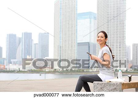 Attractive Japanese woman relaxing after training by a river downtown Tokyo, Japan View Large Photo Image Stock Photo - Attractive Japanese woman relaxing after training by a river downtown Tokyo, Japan. Fotosearch