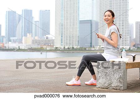 Attractive Japanese woman relaxing after training by a river downtown Tokyo, Japan View Large Photo Image Stock Photograph - Attractive Japanese woman relaxing after training by a river downtown Tokyo, Japan. Fotosearch