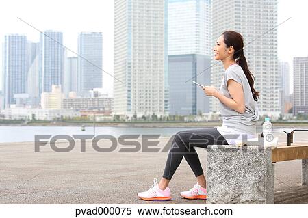 Attractive Japanese woman relaxing after training by a river downtown Tokyo, Japan View Large Photo Image Stock Photography - Attractive Japanese woman relaxing after training by a river downtown Tokyo, Japan. Fotosearch