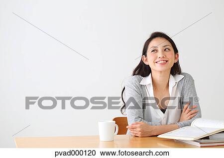 Attractive Japanese woman sitting at a table in a airy room View Large Photo Image Stock Image - Attractive Japanese woman sitting at a table in a airy room. Fotosearch