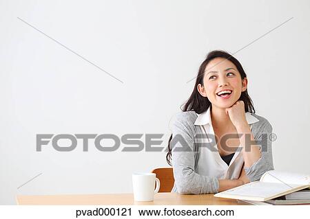 Attractive Japanese woman sitting at a table in a airy room View Large Photo Image Stock Image - Attractive Japanese woman sitting at a table in a airy room. Fotosearch