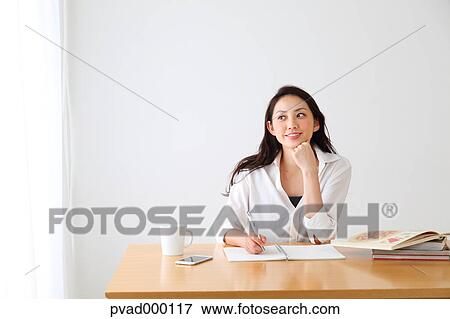 Attractive Japanese woman sitting at a table in a airy room View Large Photo Image Stock Photo - Attractive Japanese woman sitting at a table in a airy room. Fotosearch