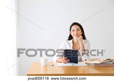 Attractive Japanese woman sitting at a table in a airy room View Large Photo Image Stock Photo - Attractive Japanese woman sitting at a table in a airy room. Fotosearch