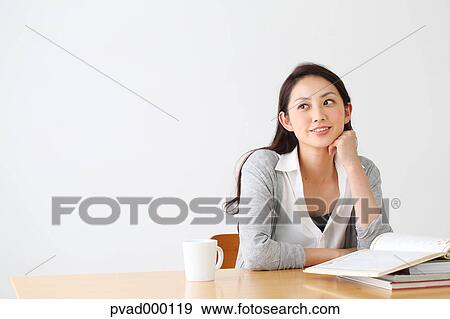 Attractive Japanese woman sitting at a table in a airy room View Large Photo Image Stock Photo - Attractive Japanese woman sitting at a table in a airy room. Fotosearch