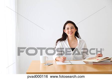 Attractive Japanese woman sitting at a table in a airy room View Large Photo Image Stock Photograph - Attractive Japanese woman sitting at a table in a airy room. Fotosearch