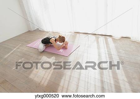 Stock Image - Attractive young Japanese practicing yoga in an airy room. Fotosearch