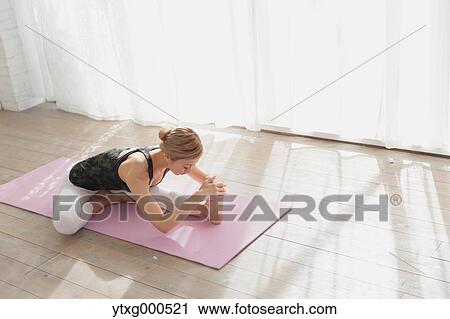Stock Image - Attractive young Japanese practicing yoga in an airy room. Fotosearch