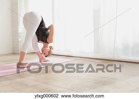 Stock Image - Attractive young Japanese practicing yoga in an airy room. Fotosearch