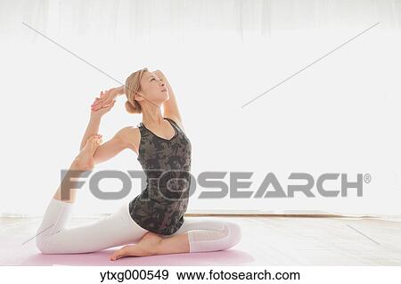 Stock Photo - Attractive young Japanese practicing yoga in an airy room. Fotosearch