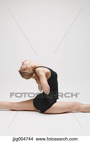 Picture - Attractive young Japanese woman wearing black pants and tank top practicing yoga on white background. Fotosearch