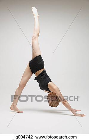 Stock Image - Attractive young Japanese woman wearing black pants and tank top practicing yoga on white background. Fotosearch