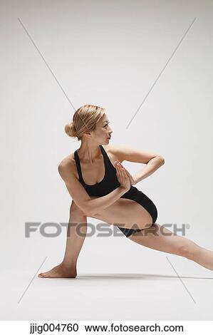Stock Image - Attractive young Japanese woman wearing black pants and tank top practicing yoga on white background. Fotosearch
