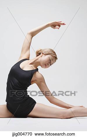 Stock Image - Attractive young Japanese woman wearing black pants and tank top practicing yoga on white background. Fotosearch