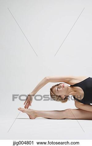 Stock Image - Attractive young Japanese woman wearing black pants and tank top practicing yoga on white background. Fotosearch