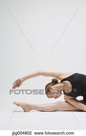 Stock Image - Attractive young Japanese woman wearing black pants and tank top practicing yoga on white background. Fotosearch