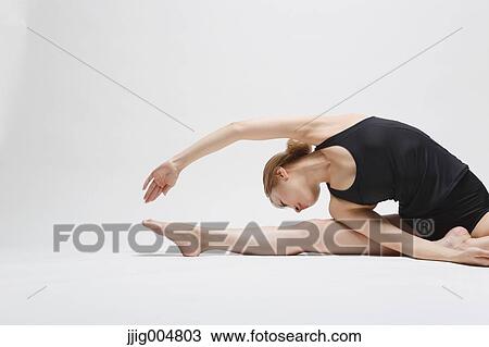 Stock Image - Attractive young Japanese woman wearing black pants and tank top practicing yoga on white background. Fotosearch