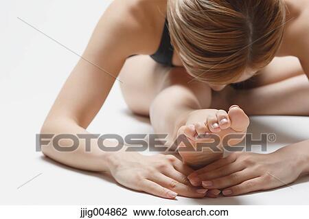 Stock Image - Attractive young Japanese woman wearing black pants and tank top practicing yoga on white background. Fotosearch