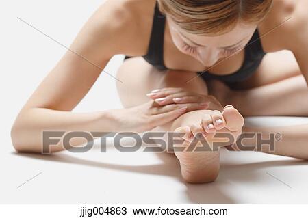 Stock Image - Attractive young Japanese woman wearing black pants and tank top practicing yoga on white background. Fotosearch