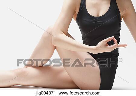 Stock Image - Attractive young Japanese woman wearing black pants and tank top practicing yoga on white background. Fotosearch