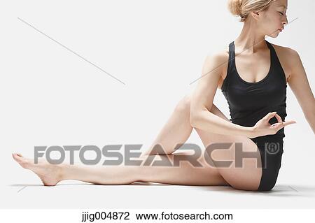Stock Image - Attractive young Japanese woman wearing black pants and tank top practicing yoga on white background. Fotosearch