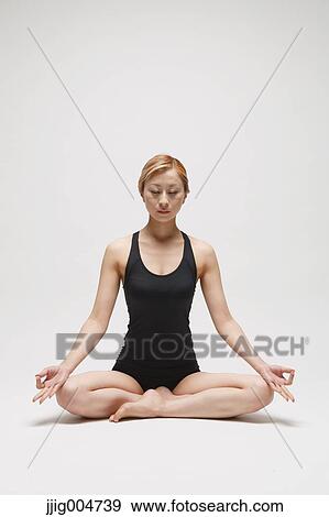 Stock Photo - Attractive young Japanese woman wearing black pants and tank top practicing yoga on white background. Fotosearch