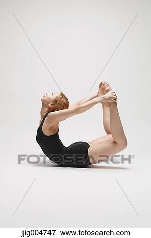 Stock Photo - Attractive young Japanese woman wearing black pants and tank top practicing yoga on white background. Fotosearch