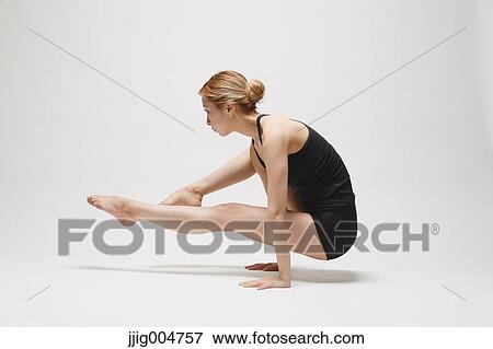 Stock Photo - Attractive young Japanese woman wearing black pants and tank top practicing yoga on white background. Fotosearch