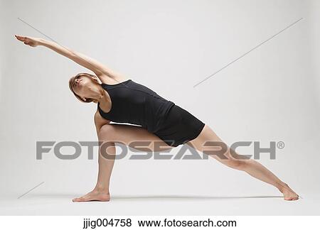 Stock Photo - Attractive young Japanese woman wearing black pants and tank top practicing yoga on white background. Fotosearch