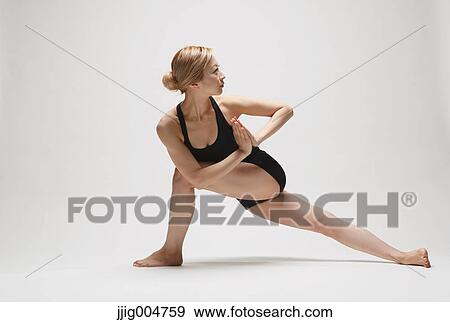 Stock Photo - Attractive young Japanese woman wearing black pants and tank top practicing yoga on white background. Fotosearch
