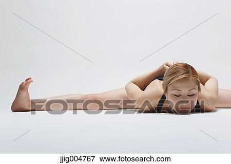 Stock Photo - Attractive young Japanese woman wearing black pants and tank top practicing yoga on white background. Fotosearch