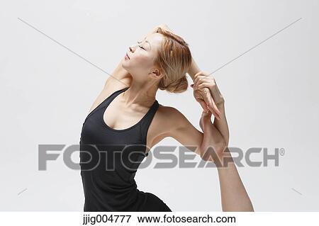 Stock Photo - Attractive young Japanese woman wearing black pants and tank top practicing yoga on white background. Fotosearch
