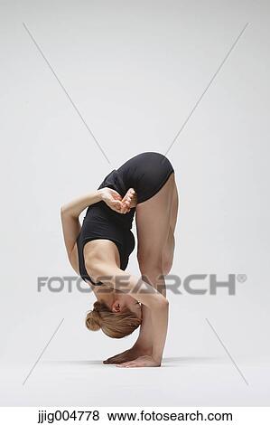 Stock Photo - Attractive young Japanese woman wearing black pants and tank top practicing yoga on white background. Fotosearch