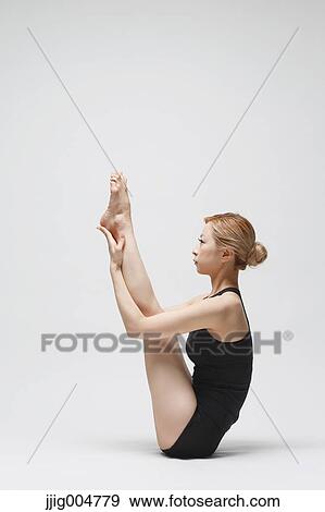 Stock Photo - Attractive young Japanese woman wearing black pants and tank top practicing yoga on white background. Fotosearch