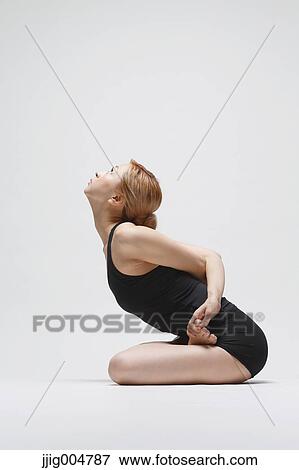 Stock Photo - Attractive young Japanese woman wearing black pants and tank top practicing yoga on white background. Fotosearch