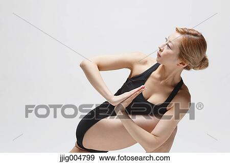 Stock Photo - Attractive young Japanese woman wearing black pants and tank top practicing yoga on white background. Fotosearch