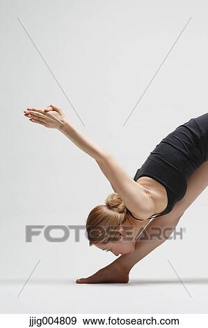 Stock Photo - Attractive young Japanese woman wearing black pants and tank top practicing yoga on white background. Fotosearch