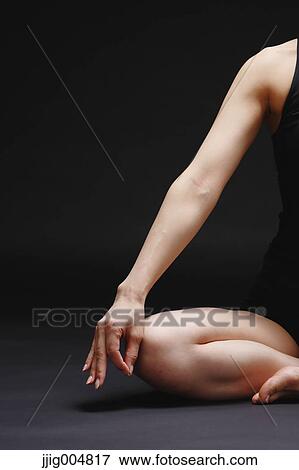 Stock Photo - Attractive young Japanese woman wearing black pants and tank top practicing yoga on black background. Fotosearch