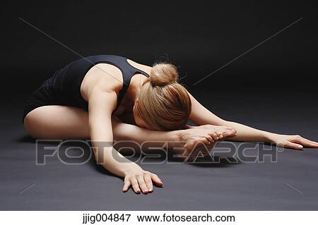 Stock Photo - Attractive young Japanese woman wearing black pants and tank top practicing yoga on black background. Fotosearch