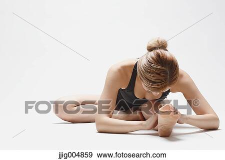 Stock Photo - Attractive young Japanese woman wearing black pants and tank top practicing yoga on white background. Fotosearch