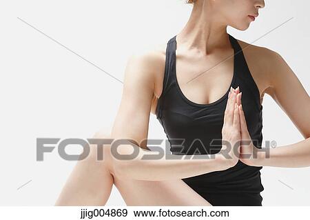 Stock Photo - Attractive young Japanese woman wearing black pants and tank top practicing yoga on white background. Fotosearch