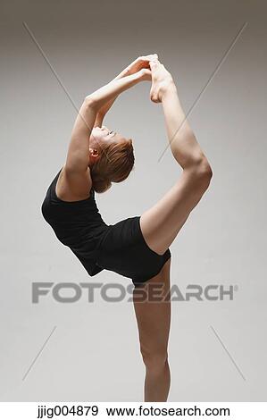 Stock Photo - Attractive young Japanese woman wearing black pants and tank top practicing yoga on white background. Fotosearch