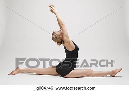 Stock Photograph - Attractive young Japanese woman wearing black pants and tank top practicing yoga on white background. Fotosearch