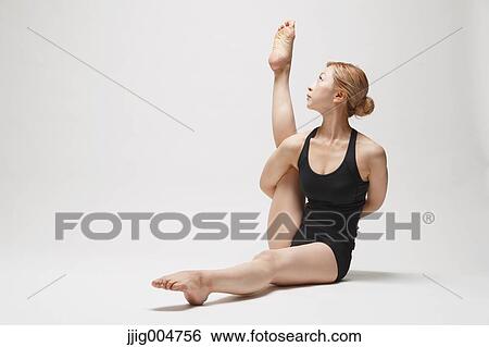 Stock Photograph - Attractive young Japanese woman wearing black pants and tank top practicing yoga on white background. Fotosearch