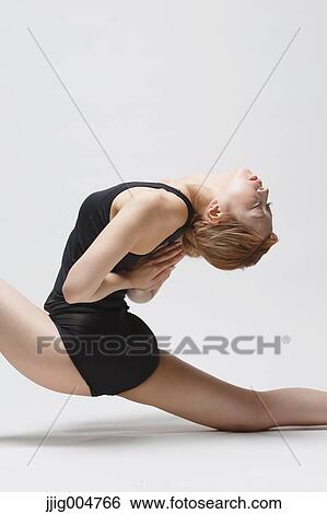 Stock Photograph - Attractive young Japanese woman wearing black pants and tank top practicing yoga on white background. Fotosearch
