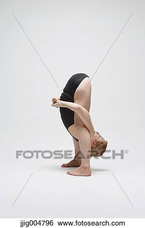 Stock Photograph - Attractive young Japanese woman wearing black pants and tank top practicing yoga on white background. Fotosearch