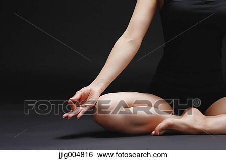 Stock Photograph - Attractive young Japanese woman wearing black pants and tank top practicing yoga on black background. Fotosearch