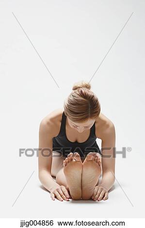 Stock Photograph - Attractive young Japanese woman wearing black pants and tank top practicing yoga on white background. Fotosearch