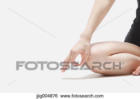 Stock Photograph - Attractive young Japanese woman wearing black pants and tank top practicing yoga on white background. Fotosearch