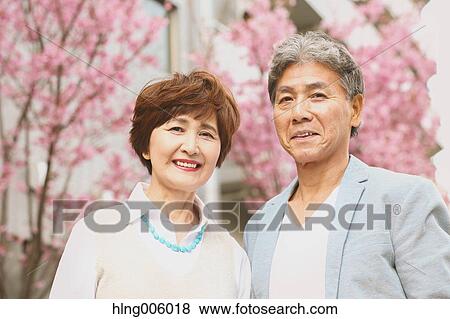 Stock Photo - Fashionable Japanese senior couple and cherry blossoms downtown Tokyo. Fotosearch